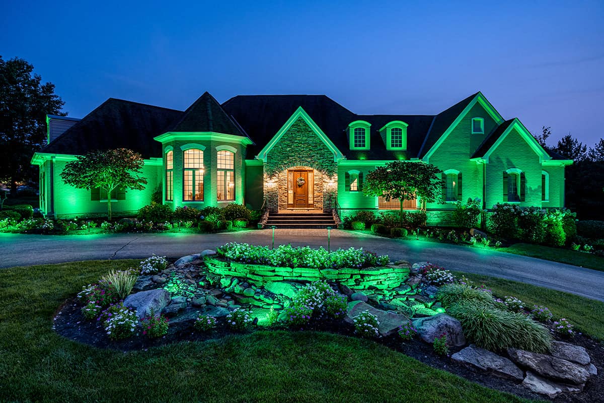 Elegant home illuminated green outdoor lighting at dusk.
