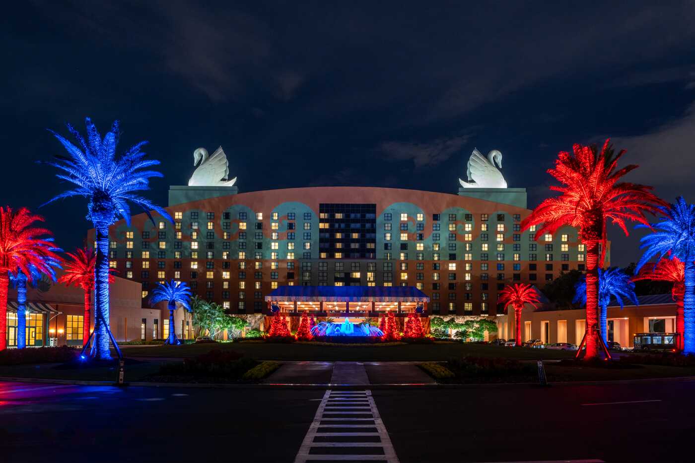 Disney Swan and Dolphin Resort at night illuminated with vibrant red and blue 9 Series Pro lights, highlighting palm trees and architectural features for a stunning visual display.