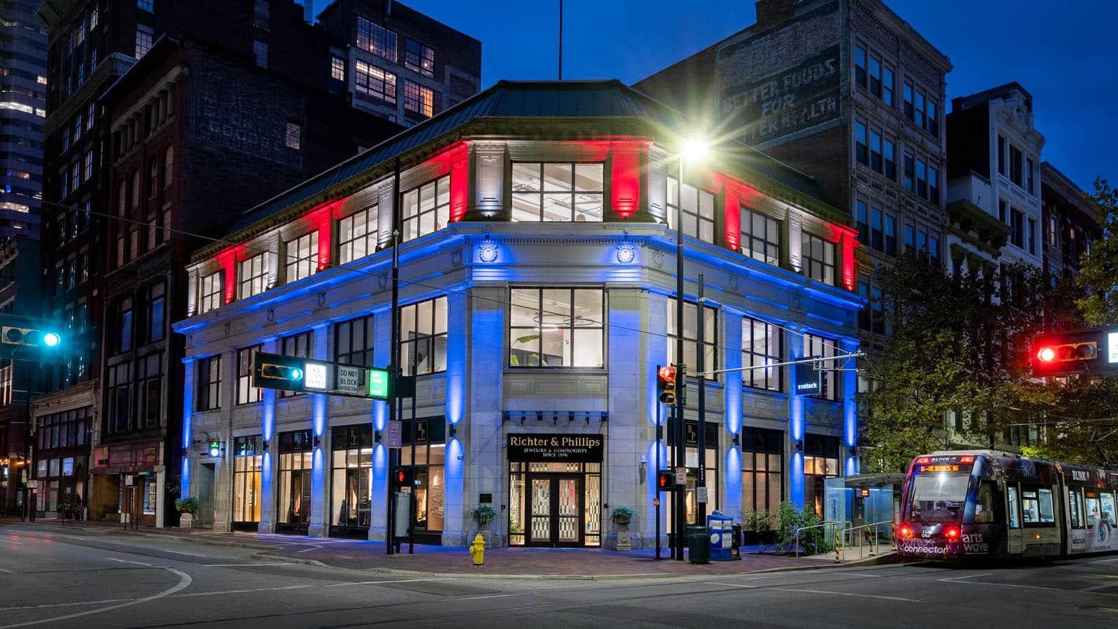 Historic corner building illuminated with red, white, and blue lighting at night.