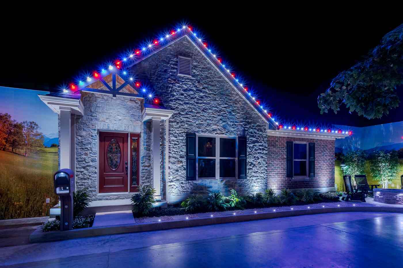House exterior at night featuring X Series Roofline Lighting in a red, white, and blue pattern, enhancing the architectural details, with pathway lighting adding to the vibrant outdoor ambiance.