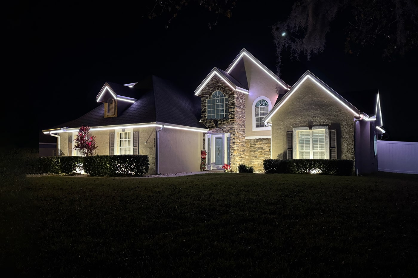 Modern home exterior with elegant permanent roofline lighting at night.