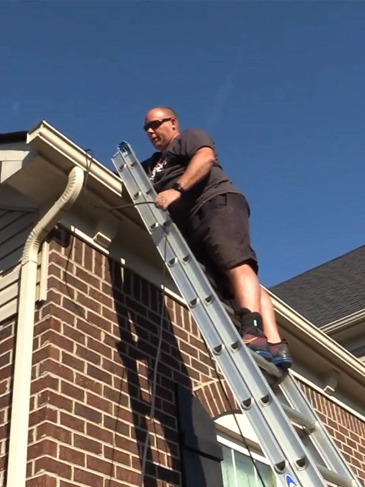 A residential lighting installer on a ladder.