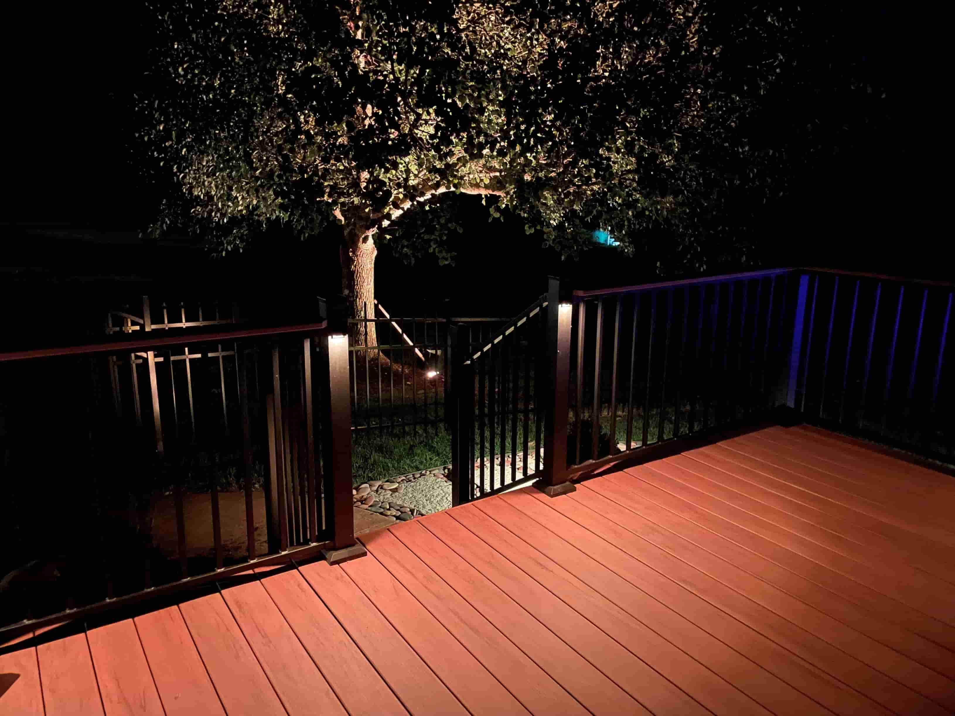 Outdoor deck lighting with warm LED post lights illuminating a wooden deck and railing at night.