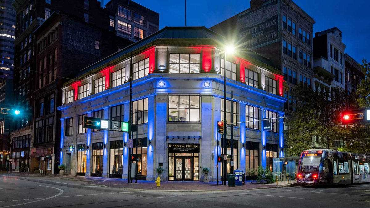 Historic corner building illuminated in red, white, and blue permanent lighting