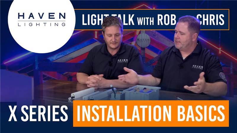 Two men in black shirts sitting at a table with Haven Lighting branding and text about X Series installation basics.